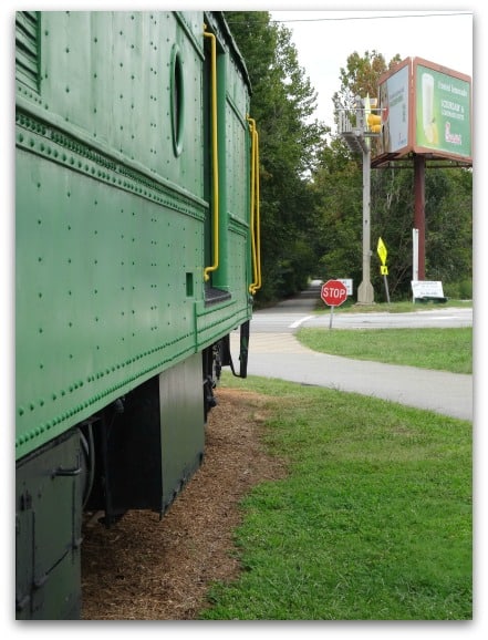 Green boxcar near a stop sign.