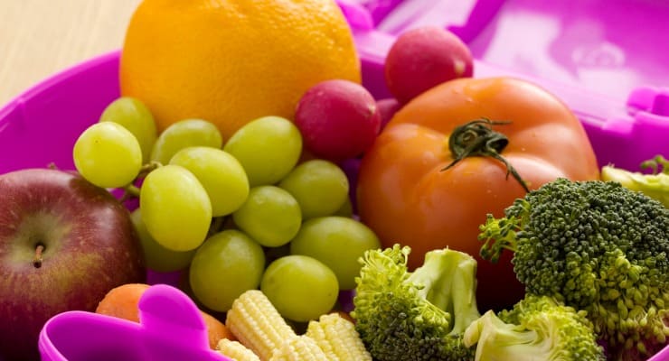 Fresh fruits and vegetables in a purple lunch box