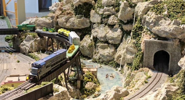 Model train on track next to rocky mountain with tunnel