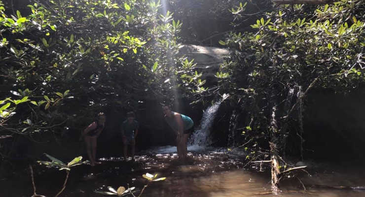 Mom and two kids splash near a small waterfall at Keowee-Toxaway State Park