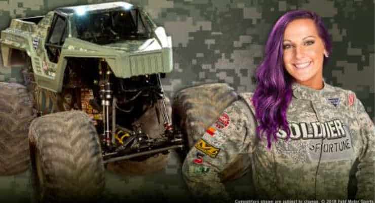 Woman wearing camo driving suit in front of a camo monster truck