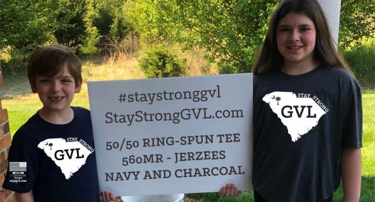 Two children wearing "stay strong GVL" shirts hold a sign with t-shirt information.