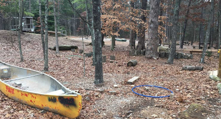 An old yellow canoe sitting in a natural playground
