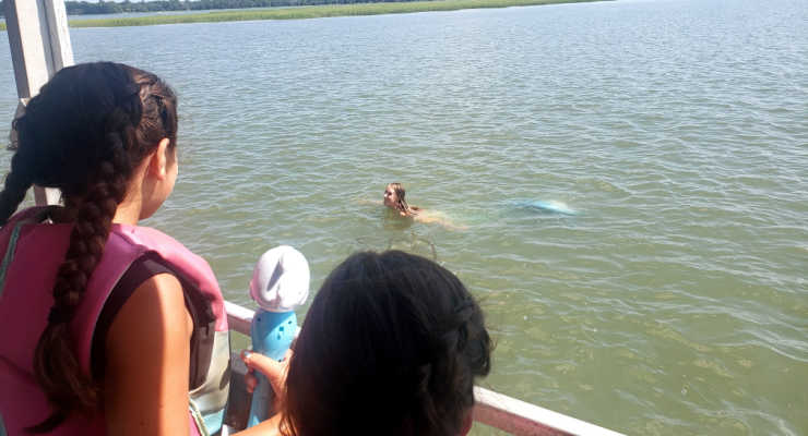 Children on boating looking at a mermaid in the water