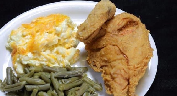 A plate with fried chicken, cheesy potatoes, and green beans.