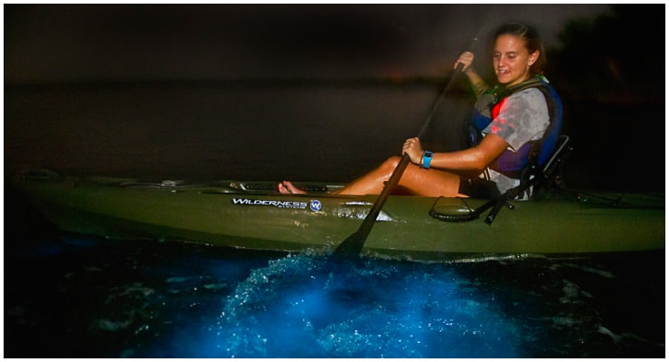 woman in kayak paddling thru biolum waters