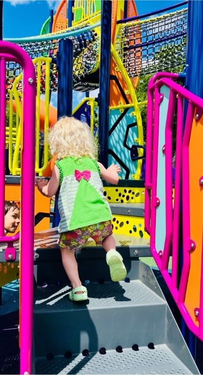 Image of child climbing up stairs on new playground equipment.