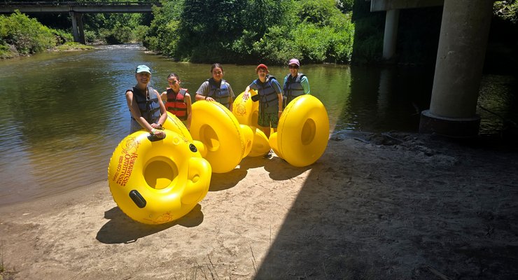 Family holding yellow tubes ready to go tubing on the French Broad River at Headwaters Outfitters in Rosman NC
