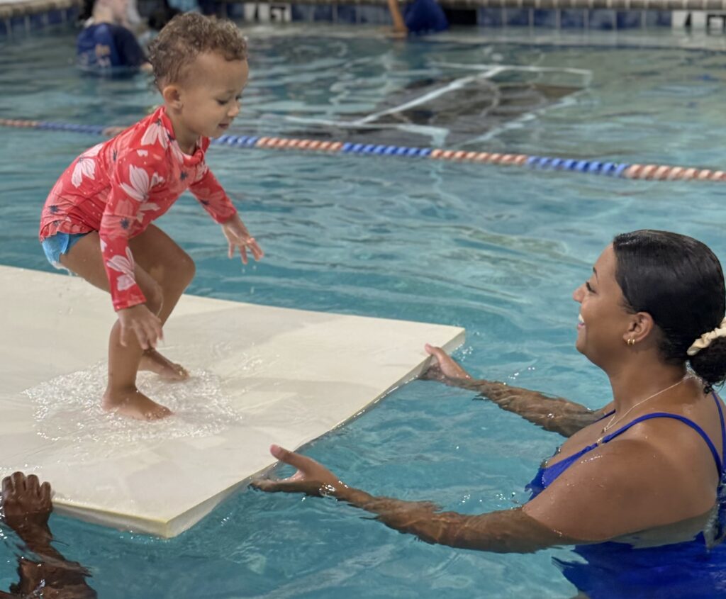 Embler Swim school | Child jumping in water with guide