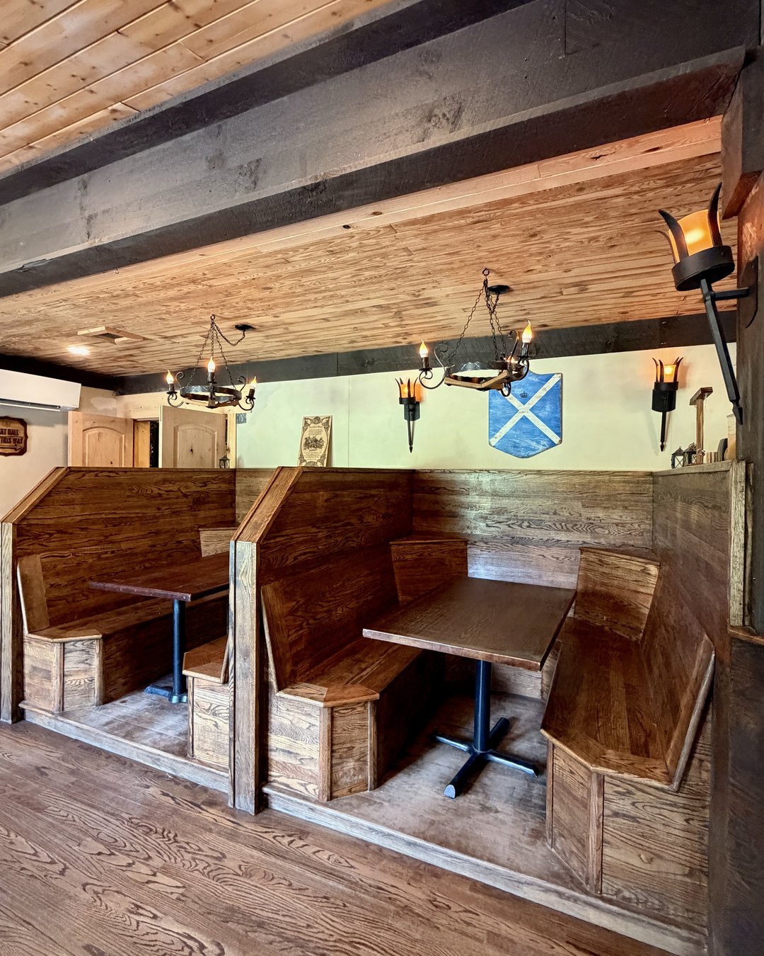 Fae Nectar medieval tavern interior with wooden booths iron chandelier torch sconces and shield decor