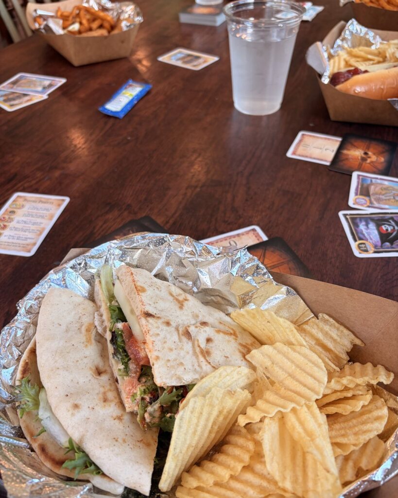Flatbread sandwich with chips from Fae Nectar Celtic Kitchen with fantasy themed playing cards on the wooden table