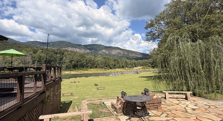 Fae Nectar outdoor stone patio with fire pit bench seating lawn and mountain and water views