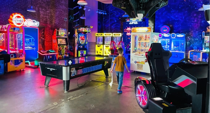 A young boy walks into a glowing arcade surrounded video games