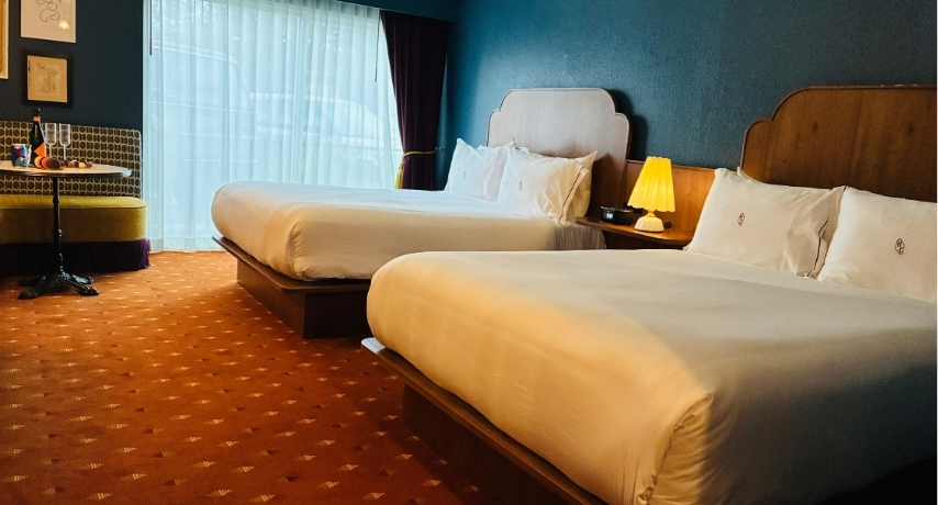 Two queen-sized beds in a hotel room with vintage color tones