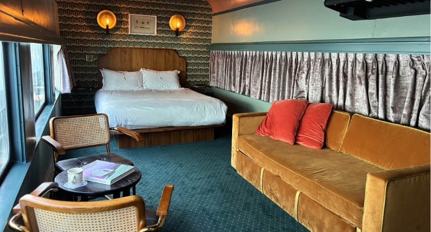 A luxurious train carriage with queen bed, sofa, and a small round table with two chairs
