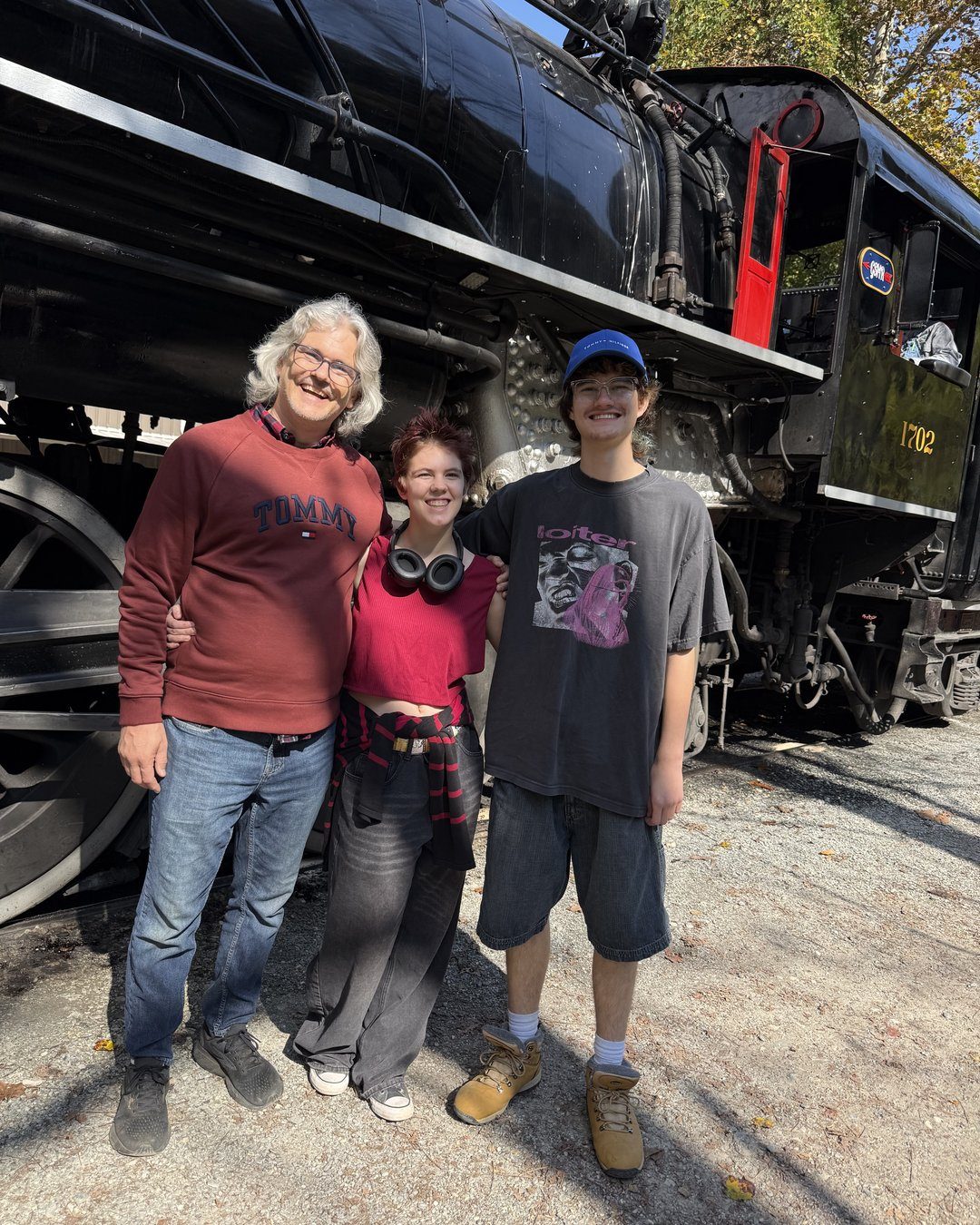 Family posing in front of a black steam locomotive at the Great Smoky Mountains Railroad depot in Bryson City, NC