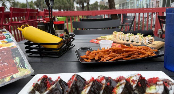 Plate of sushi rolls and sweet potato fries on an outdoor patio near the Myrtle Beach Boardwalk